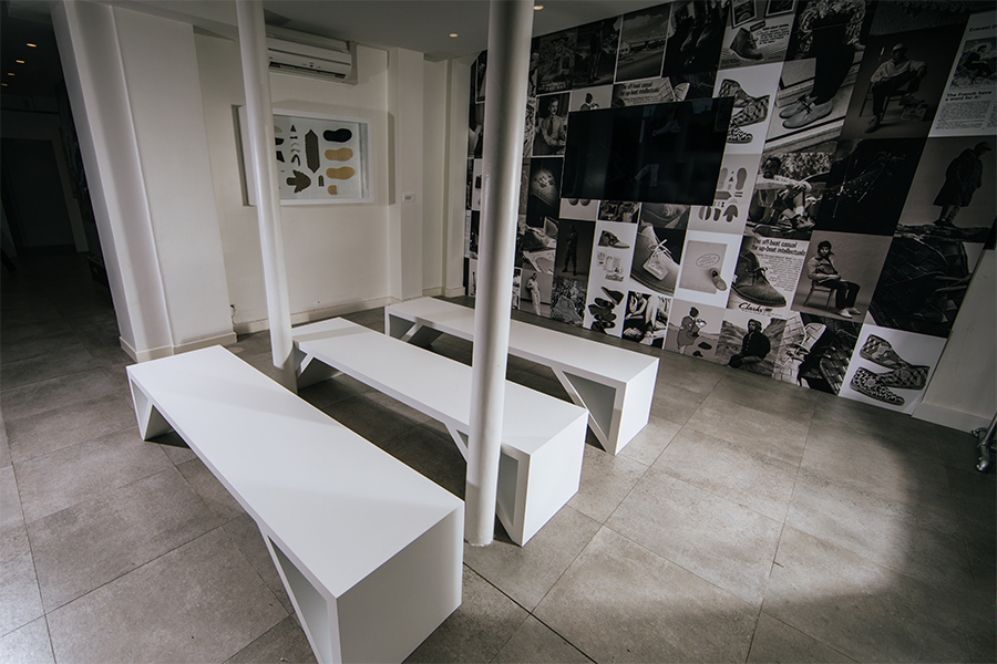 Showroom for Clarks, with three white benches, television and wall vinyl, black and white photography