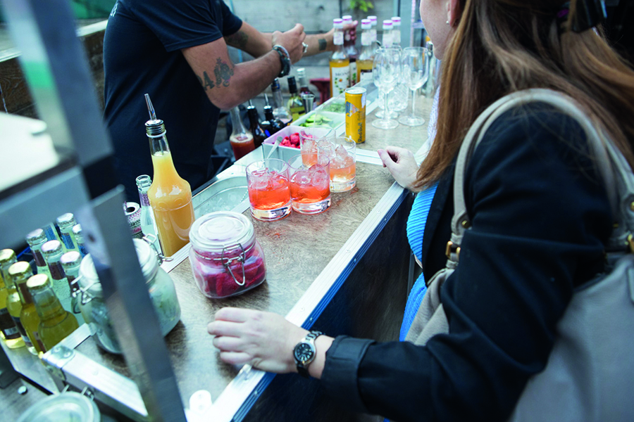 Woman standing at bar, with cocktails and lots of drinks being made